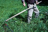 Man mowing grass with a scythe