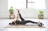 A woman stretching on a yoga mat in a sunny room