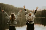 Two women celebrating by a lake