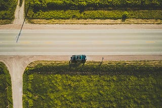 a car stopped on a big highway near a dirt road