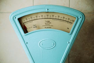 A close-up of a vintage blue analog weight scale.