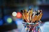 A jar filled with paintbrushes.