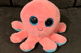 smiling pink octopus stuffed animal with large blue eyes
