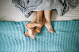 A image showing a couple’s feet lying in bed