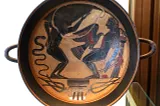 An ancient Greek black-figure kylix showing Prometheus bound to a pillar with an eagle pecking at his liver.