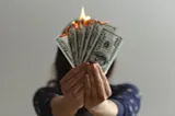 A woman holds burning money