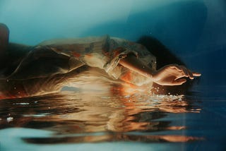 A woman in a colorful dress falling face-first into water.