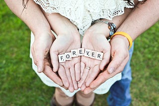 Couple holding Scrabble tiles that spell FOREVER in their hands