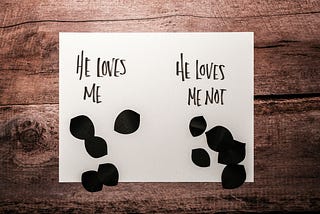 The left side of the card says, “He loves me,” and the right side says, “He loves me not.”