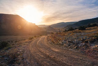 A desert road at sunset, mountains in the background.