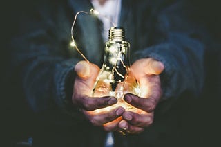 Person holding glowing lightbulb.