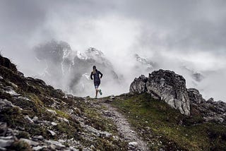 A lone trail runner fades into the distant mountains.