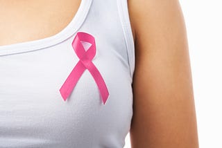 pink ribbon pinned on a woman’s white tank top