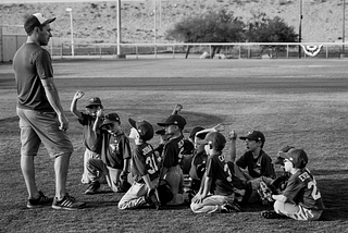 Little league coach talking with his team on the field