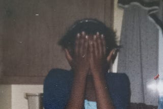 Author Photo: Tween Black Girl, awkward, lanky, covering her face.