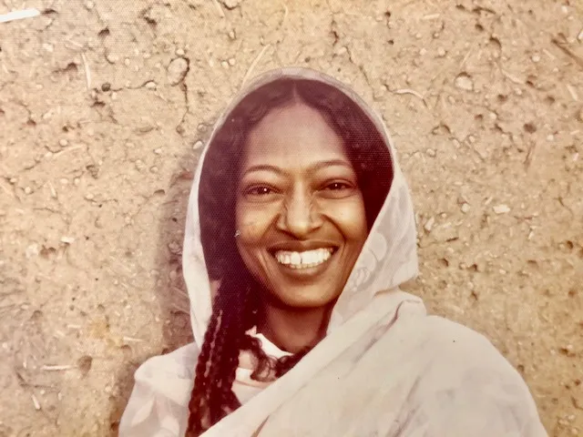 Photo of Fiza, mother of Nafisa standing in front of her mud brick house in Sudan