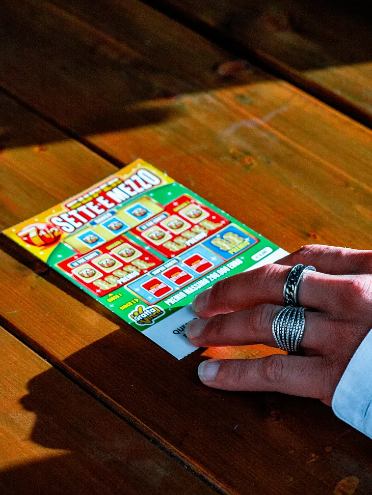 Hand touching jackpot tickets on a wooden surface.