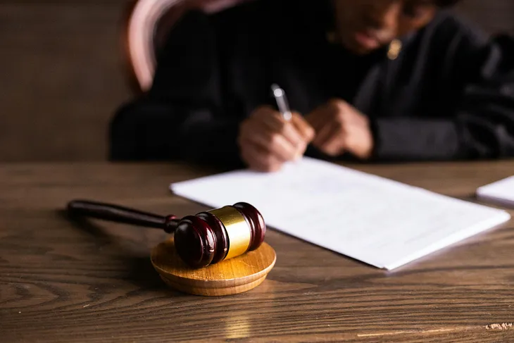 Picture of a Judge signing a document. A gavel is next to the document.