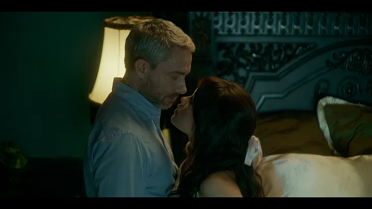 Martin Freeman as Jonathan Miller and Jenna Ortega as Cairo Sweet standing close together, almost kissing, in “Miller’s Girl”.