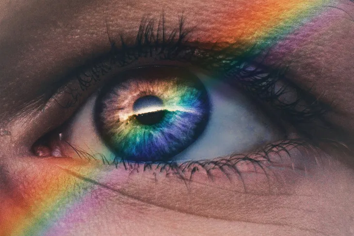 A close up of an eye with a rainbow over it.